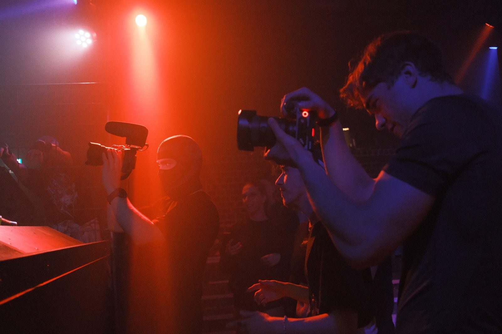 Timon photographing at a club event under red light